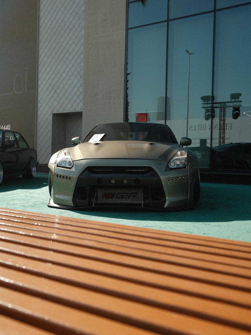 A sleek gray sports car parked in front of a modern building with large glass windows.