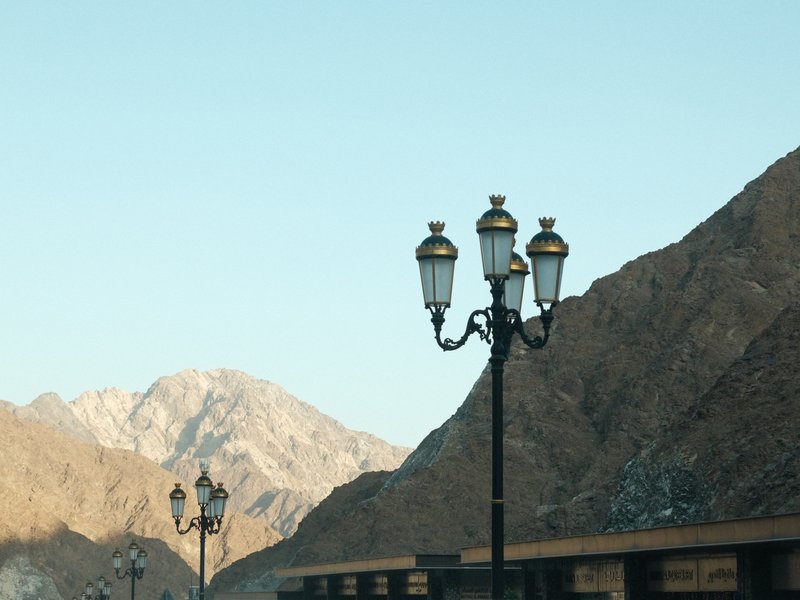 Street lamps against a backdrop of mountains under a clear sky.