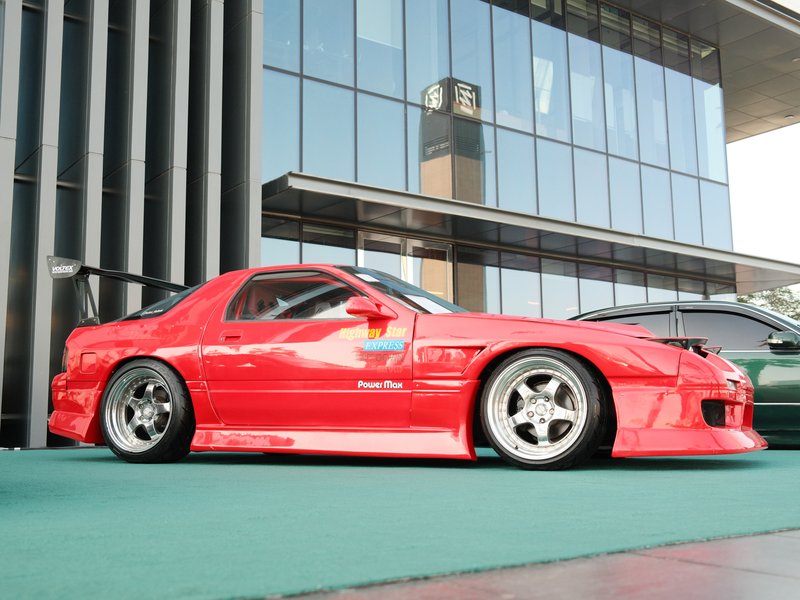 A vibrant red sports car parked in front of a modern glass building, showcasing its sleek design.