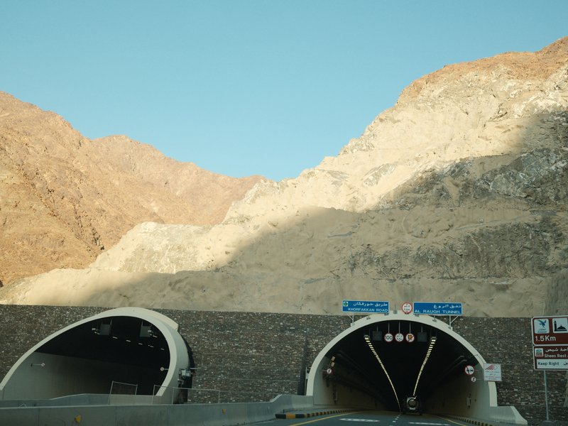 Two tunnel entrances in a rocky mountain landscape under a clear blue sky.