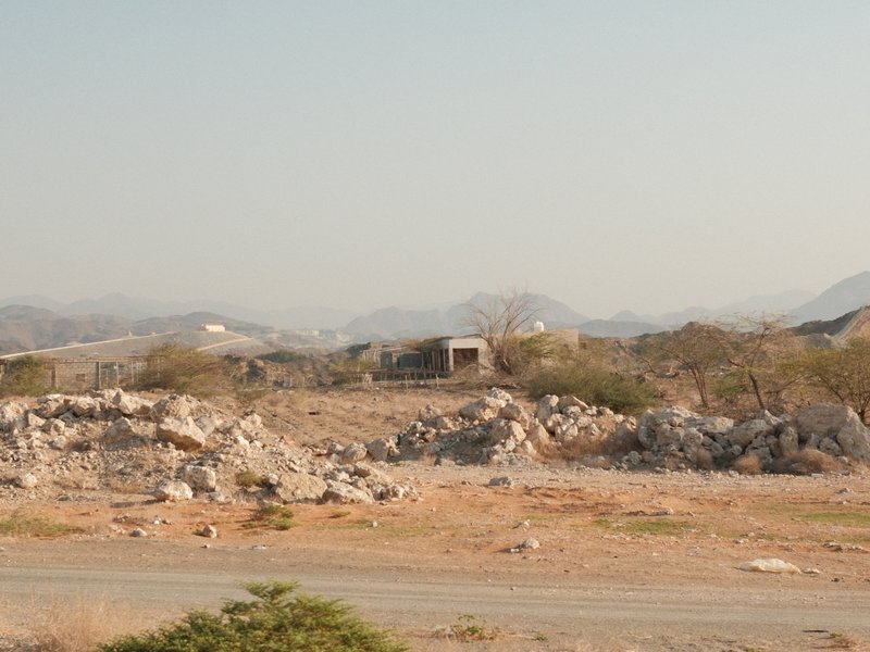 A barren landscape with rocky terrain and distant mountains under a clear sky.