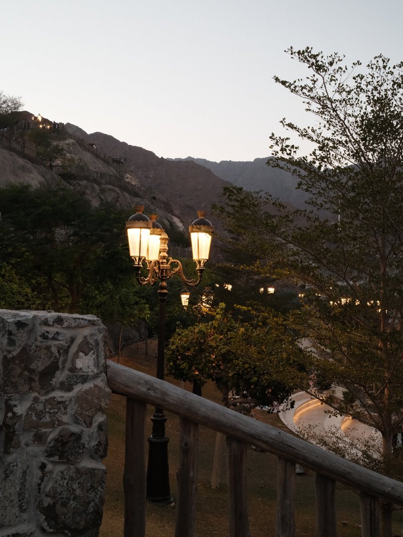 A scenic view of lanterns along a pathway with mountains in the background during twilight.