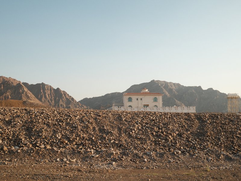 A distant view of a white building against rocky mountains under a clear sky.