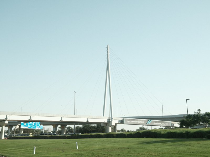 A modern cable-stayed bridge against a clear sky, with green grass in the foreground.