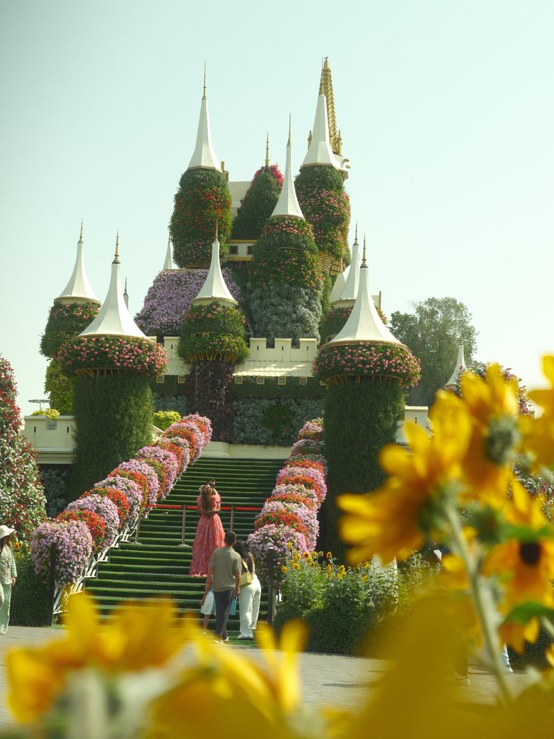 A whimsical castle surrounded by colorful flowers and greenery under a bright sky.