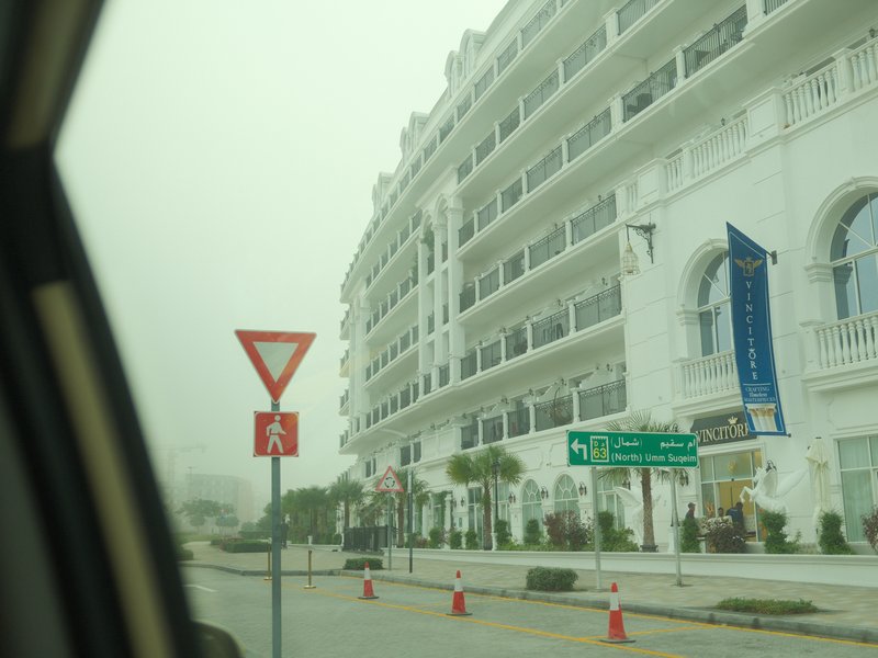 A view of a white building with a yield sign in the foreground, seen from a car window in foggy weather.