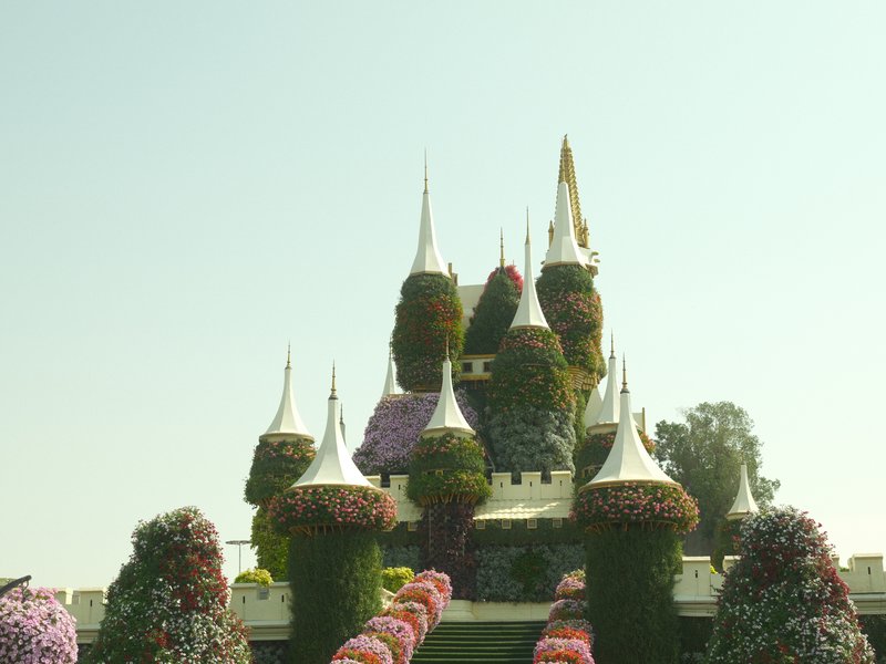 A whimsical flower-covered castle with pointed towers and colorful floral arrangements in the foreground.