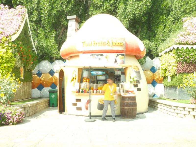 A whimsical mushroom-shaped food stall with a person in a yellow shirt standing in front.