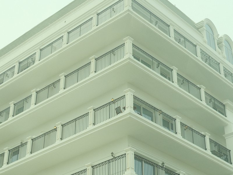 Close-up of a modern building with multiple balconies and large windows under a hazy sky.