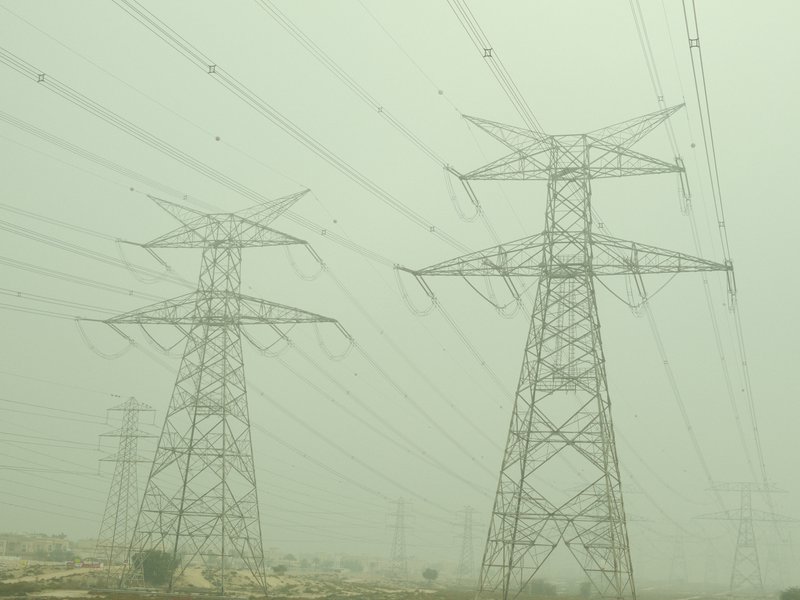 Two tall power transmission towers silhouetted against a foggy sky.