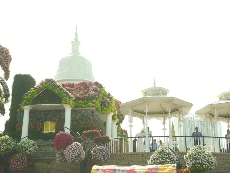 A floral-themed structure with white domes and surrounding flowers in a bright, misty atmosphere.