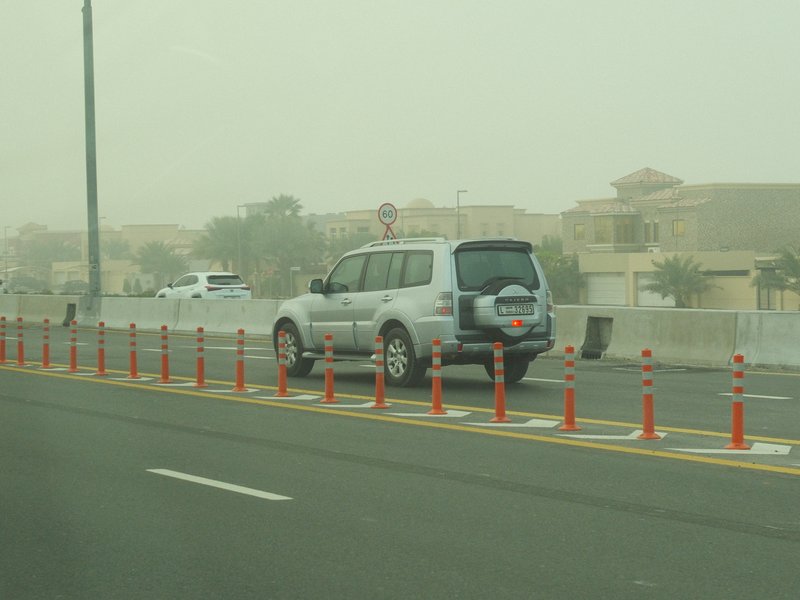 A vehicle on a dusty road with construction cones in a hazy environment.