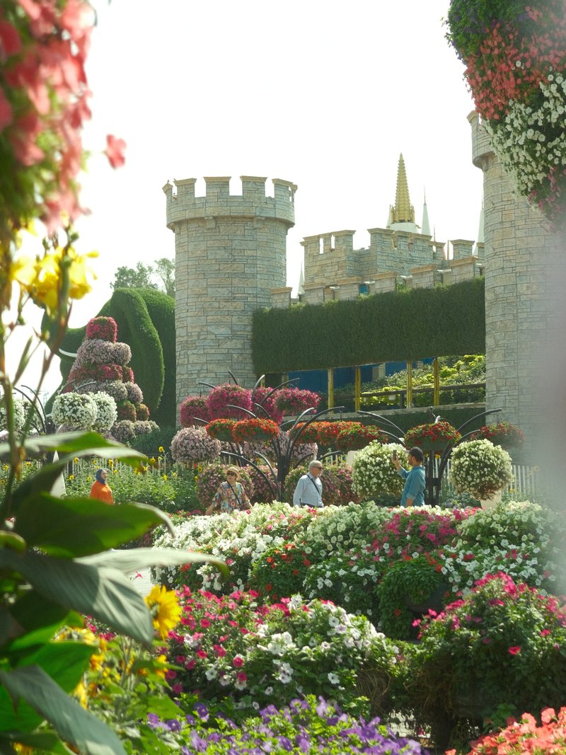 A vibrant garden scene with colorful flowers in front of a castle-like structure.