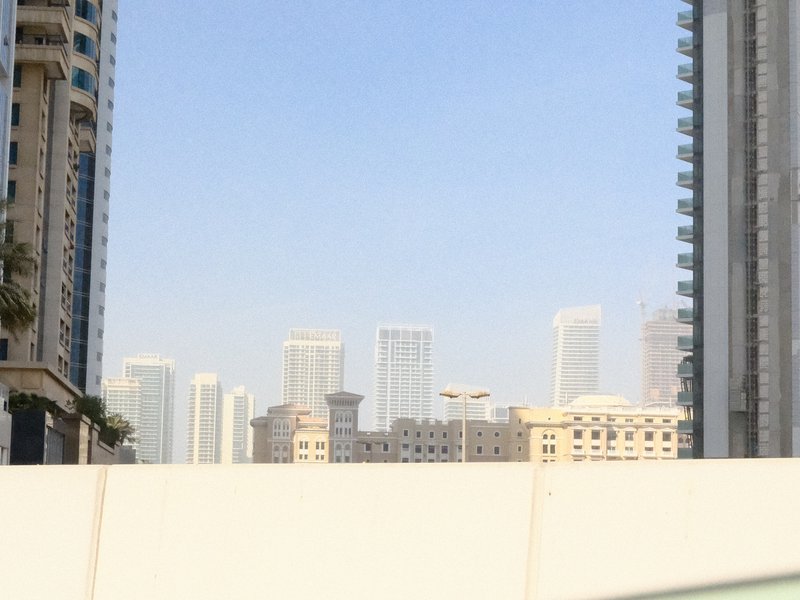 A city skyline with tall buildings under a clear blue sky, viewed from a low angle.