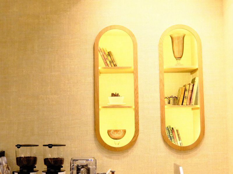 Interior scene featuring two oval shelves with books and decorative items against a softly lit wall.