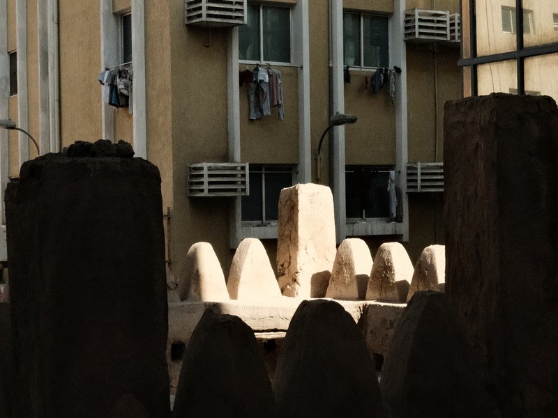 View of a building with clothes hanging from windows, framed by stone structures in the foreground.
