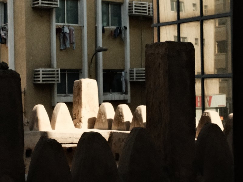 A view of a cityscape with stone structures in the foreground and buildings in the background.