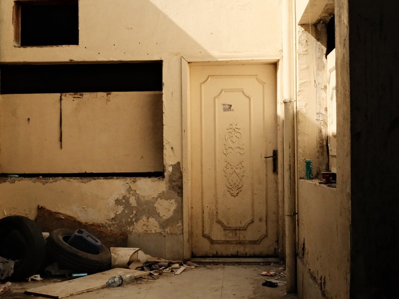 A weathered door in a dilapidated building surrounded by debris and peeling walls.