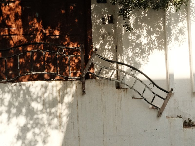 A unique perspective of a staircase with a metal railing casting shadows on a white wall.