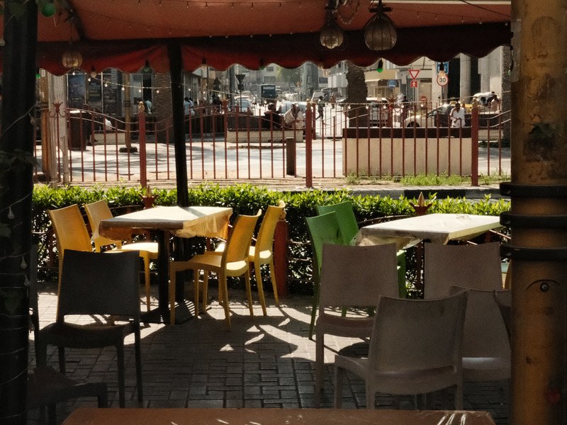 Colorful chairs in a cafe setting with sunlight filtering through a canopy.