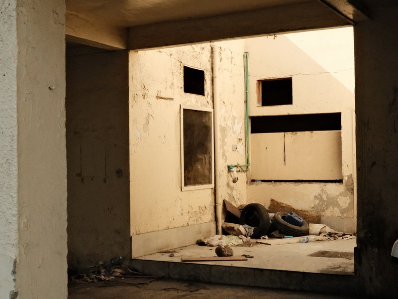 An abandoned interior space with peeling walls and scattered debris, illuminated by soft light.