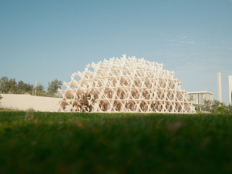 A modern architectural structure with a geometric design set against a clear blue sky.