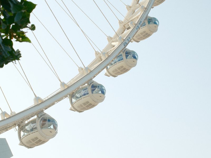 Close-up of a ferris wheel with white cabins against a clear sky.