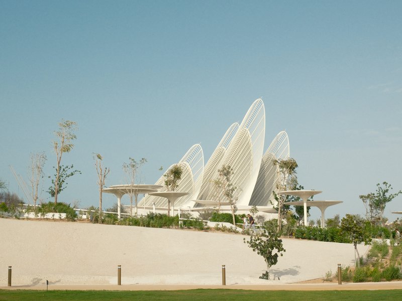 Modern architectural structure with curved white elements against a clear blue sky.