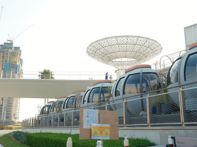A row of gondolas at a modern urban cable car station with a large canopy overhead.