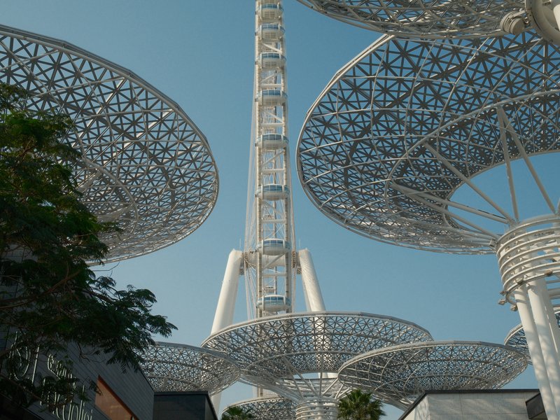 A modern architectural structure with large, circular canopies and a tall tower against a clear blue sky.