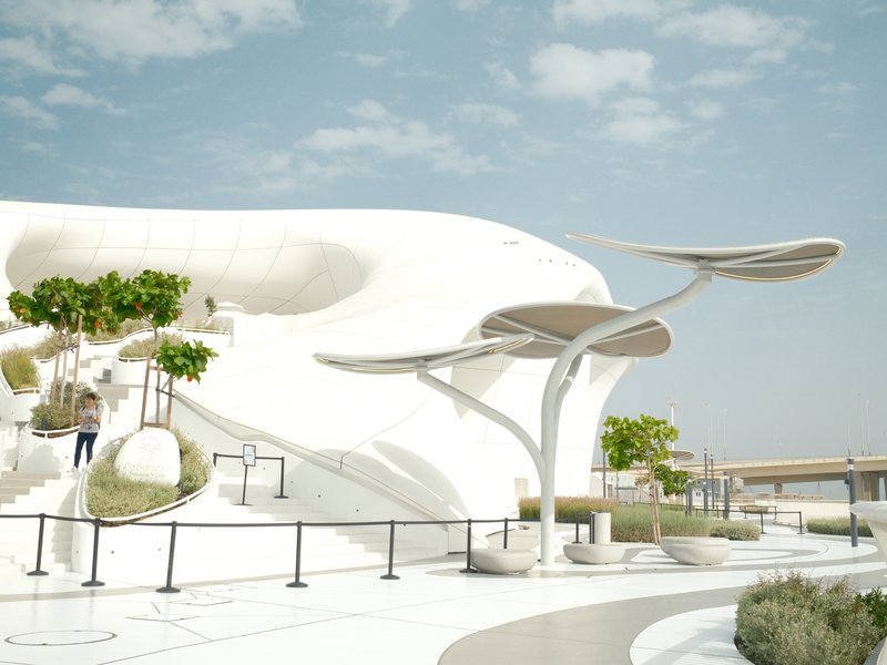 Modern architectural structure with curved white surfaces and green plants under a blue sky.