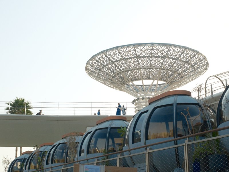 A modern gondola lift station with several gondolas lined up below a large, intricate canopy structure.