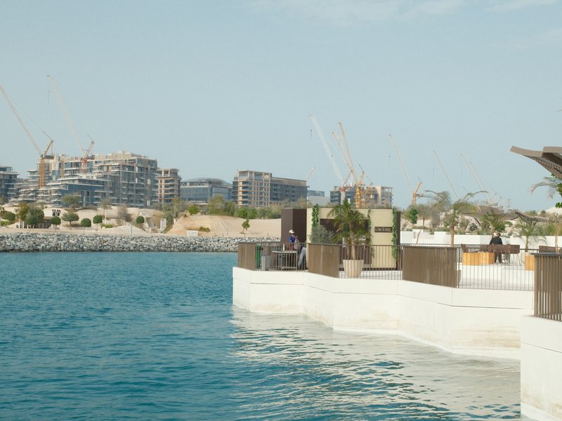 A waterfront scene featuring a modern structure with a view of buildings across the water.