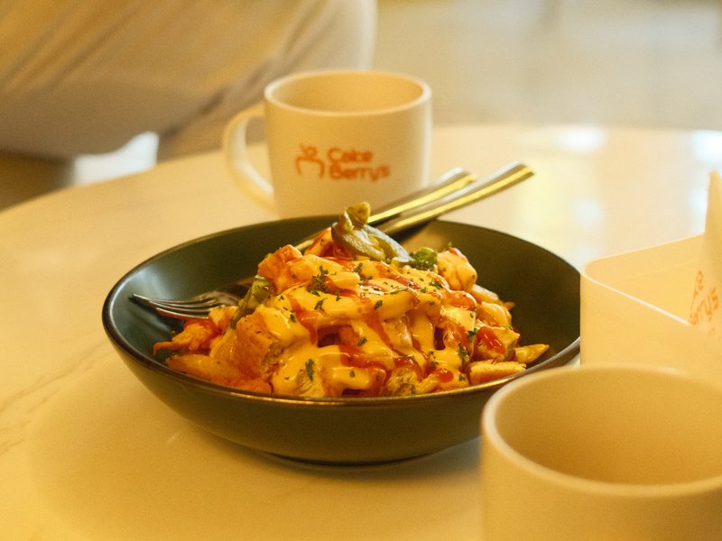 A close-up of a bowl of colorful stir-fried noodles with vegetables on a white table.
