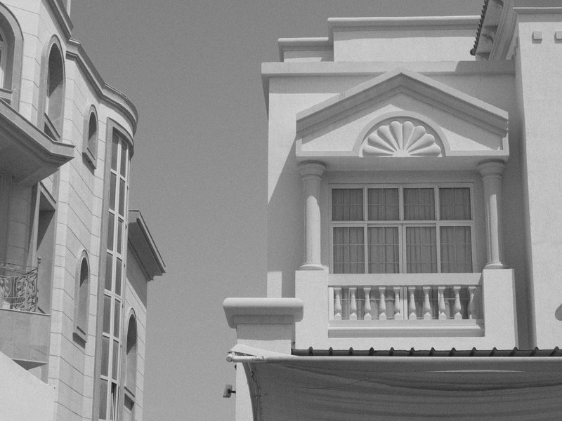 Black and white photo of a building facade with classical architectural features and a neighboring structure.