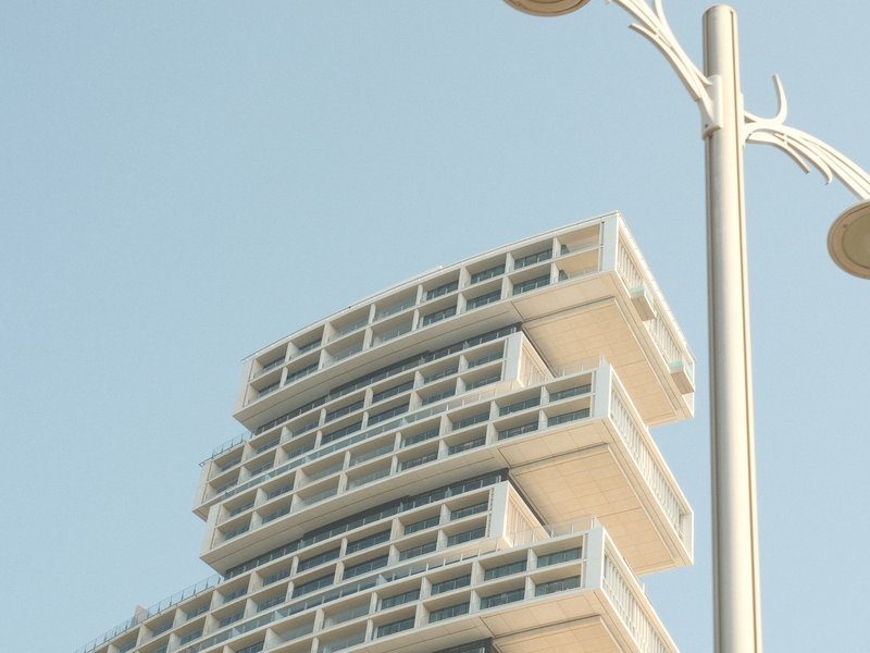 Close-up of a modern architectural building with stacked balconies against a clear blue sky.