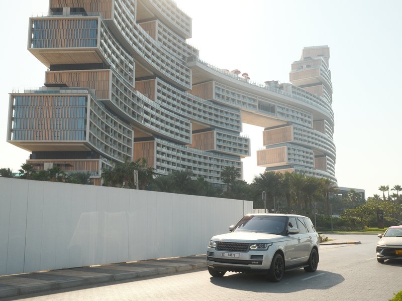 Modern architectural building with unique design and a car passing by on a sunny day.
