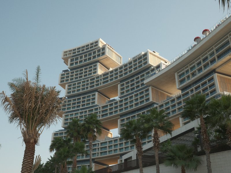 Modern architectural building with stacked blocks and palm trees in the foreground.