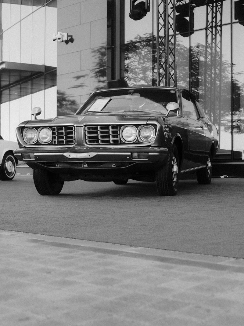 Classic car parked on a stage with modern architecture in the background.