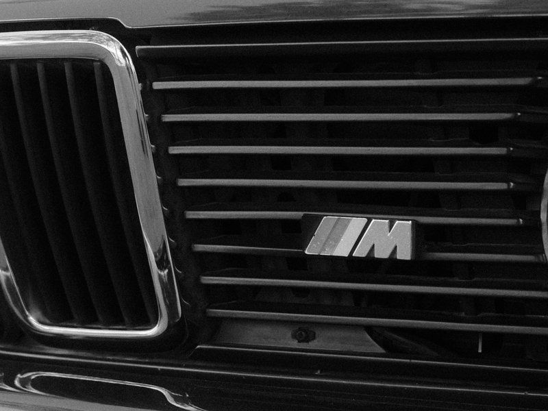 Close-up of a black car's front grille featuring the BMW M logo.
