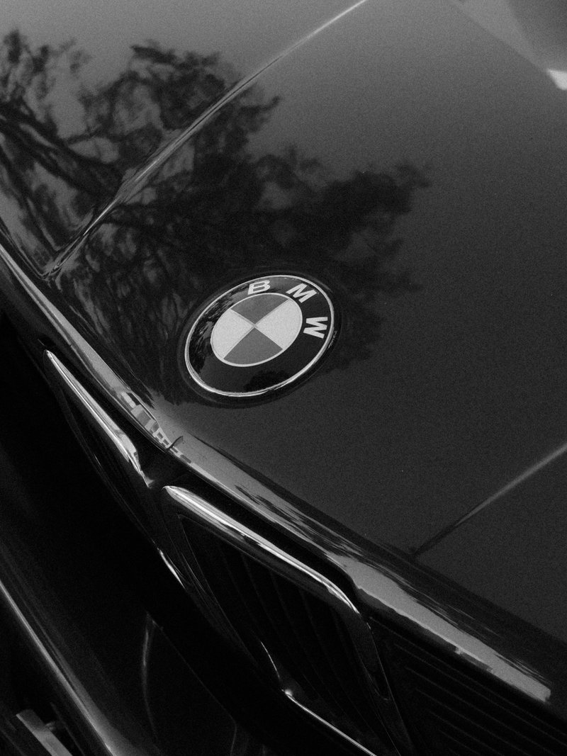 Close-up of a BMW car emblem on a sleek black surface with reflections.