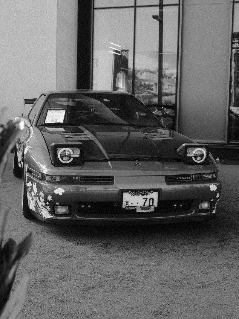 A vintage car parked indoors with a sleek design and floral decals on the front.