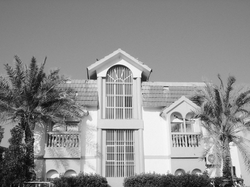 A large, modern house with palm trees in front, captured in black and white.