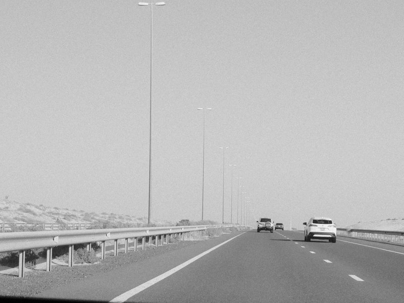 A highway scene with vehicles and tall streetlights under a clear sky.