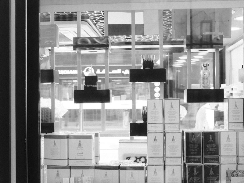 A monochrome image of a shop window displaying stacked boxes and products behind glass.