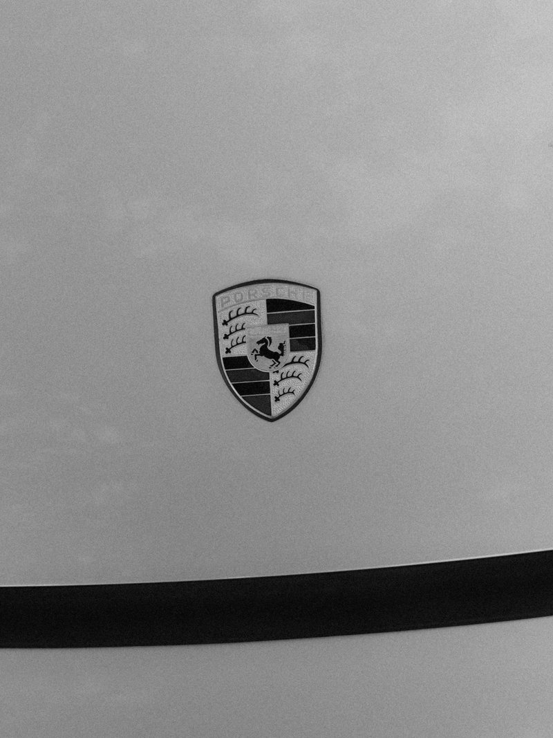 Close-up of a Porsche emblem on a car's surface with a sleek design.