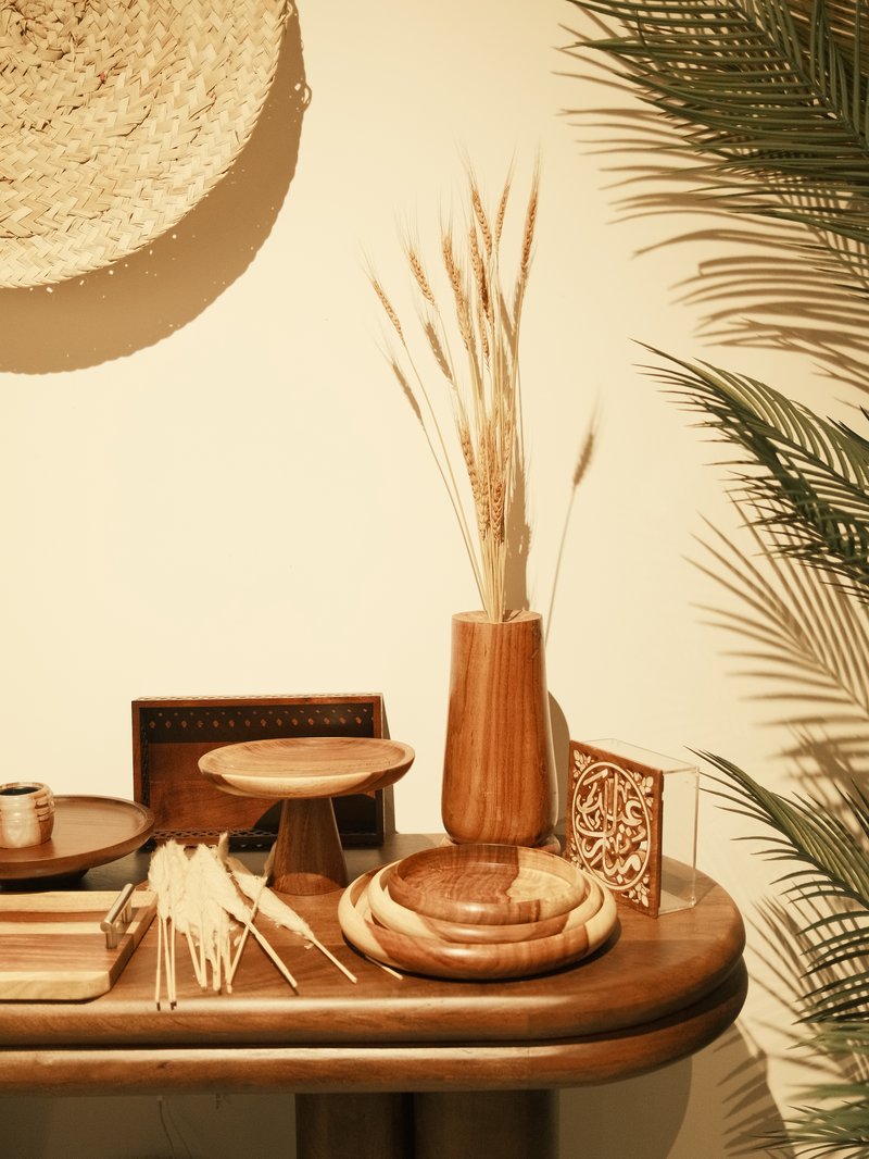 A wooden table adorned with decorative items including vases, bowls, and woven art against a light wall.