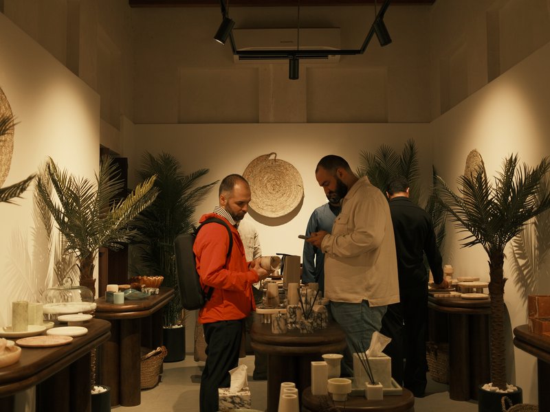 Two men interacting in a cozy indoor shop filled with decorative items and plants.