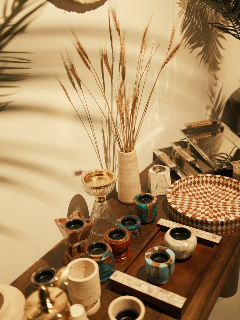 A collection of decorative items including vases, cups, and a woven basket on a wooden table.