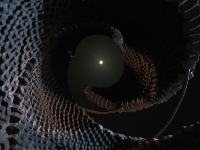Abstract spiral structure with a bright light source at the center, creating a dramatic effect.